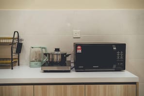 Una cocina con microondas, hervidor y una olla sobre la encimera.
