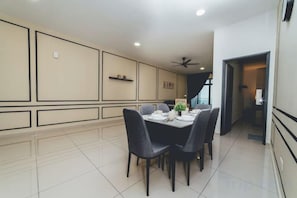 A dining area with a table set for four, surrounded by chairs, in a room with a tiled floor and a ceiling fan. - Marina Residence 3BR Shores Haven nr Midvalley CIQ (Plentong)