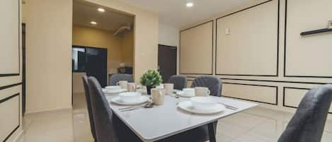 Un comedor con una mesa dispuesta para cuatro, sillas y una planta pequeña en la mesa.