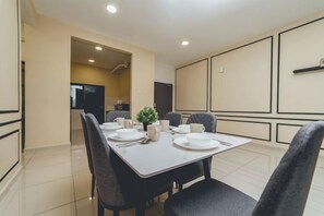 A dining area with a table set for four, chairs, and a small potted plant. - Marina Residence 3BR Shores Haven nr Midvalley CIQ (Plentong)