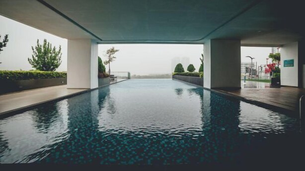 A modern indoor swimming pool with a clear view of the surrounding greenery and buildings. - Marina Residence 3BR Shores Haven nr Midvalley CIQ (Plentong)