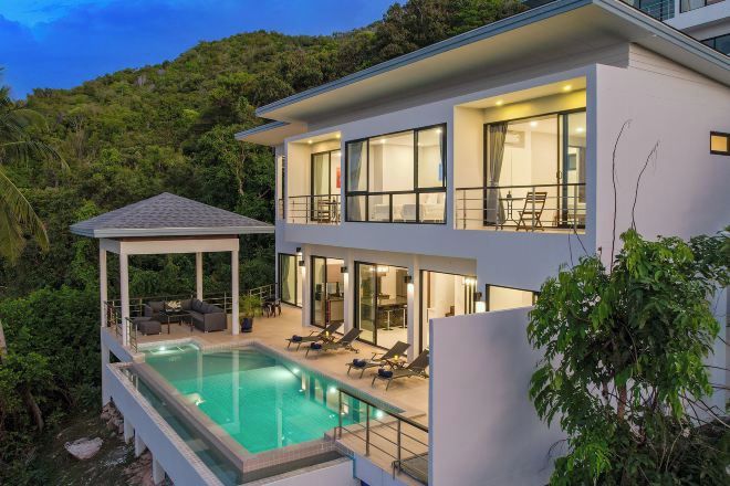 A modern two-story house with a swimming pool, outdoor seating, and a covered patio.