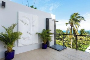 A balcony with a white wall, a large abstract sculpture, and potted plants. - L'Esterel Villa - A Tropical Oasis at Maenam Hills (Koh Samui)