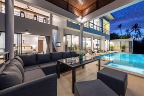 Un interior residencial moderno y de varios niveles con piscina, zona de estar exterior y una escalera.