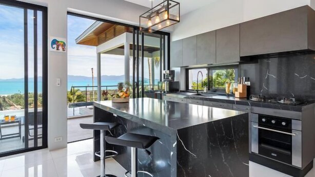 A modern kitchen with a large island, black marble countertops, and stainless steel appliances. - L'Esterel Villa - A Tropical Oasis at Maenam Hills (Koh Samui)