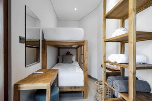 A bunk bed with a wooden headboard, a bedside table, and a mirror. There is a wooden shelf unit with folded towels. - Villa Juke by BaliSuperHost (Bali)