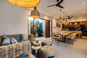 A modern living room with a sofa, ottomans, and a dining area with a table and chairs. - Villa Juke by BaliSuperHost (Bali)