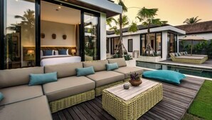 A modern villa with a large outdoor living area, including a sofa set, a coffee table, and a pool.