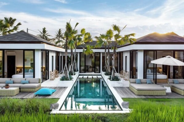 A modern house with a central pool, outdoor seating, and palm trees. - Villa Juke by BaliSuperHost (Bali)