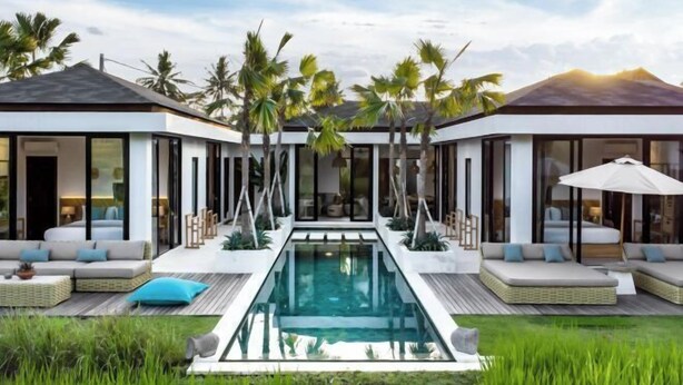 A modern villa with a central pool, outdoor seating, and palm trees.