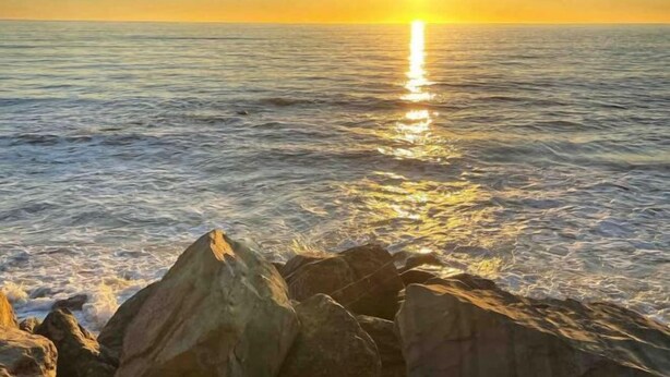 A sunset over the ocean with rocks in the foreground. - Beachside Breakaway Glenelg South – 200m to the Beach (Glenelg South)