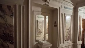 A hallway with ornate wall moldings and a marble-like design on the doors.