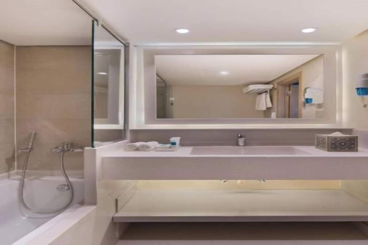 A modern bathroom with a glass shower enclosure, a large mirror, and a vanity with a sink and countertop.