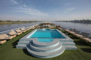 A pool area with lounge chairs and a view of the water. - Jaz Celebrity Nile Cruise - Every Saturday from Luxor for 07 & 04 Nights (At Tod)