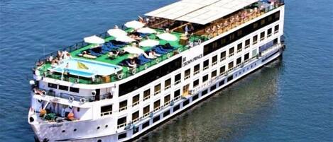 Un barco de recreo fluvial con varios niveles, zonas de estar al aire libre y cubierta superior protegida.