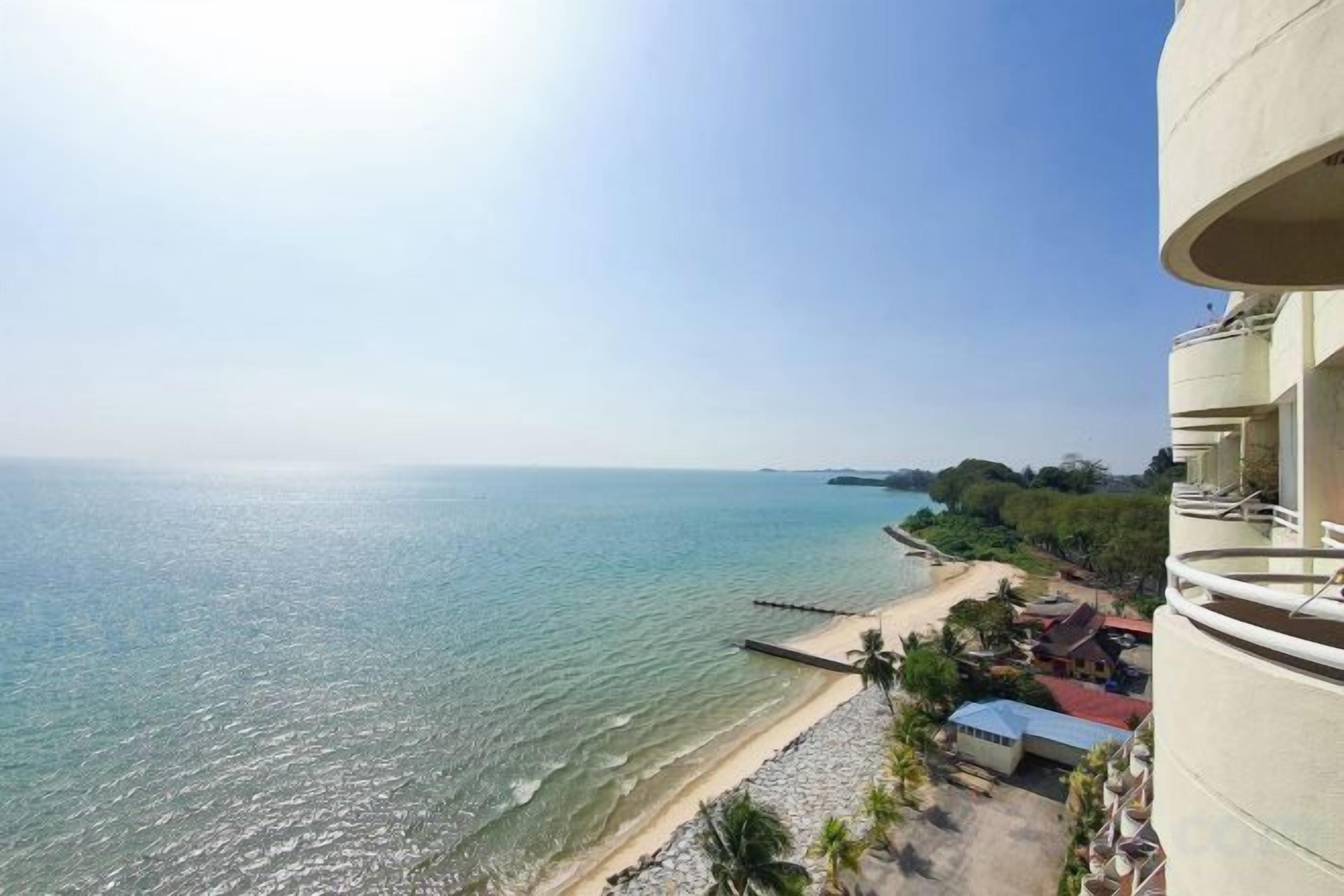 A coastal view from a balcony overlooking a beach and the sea.