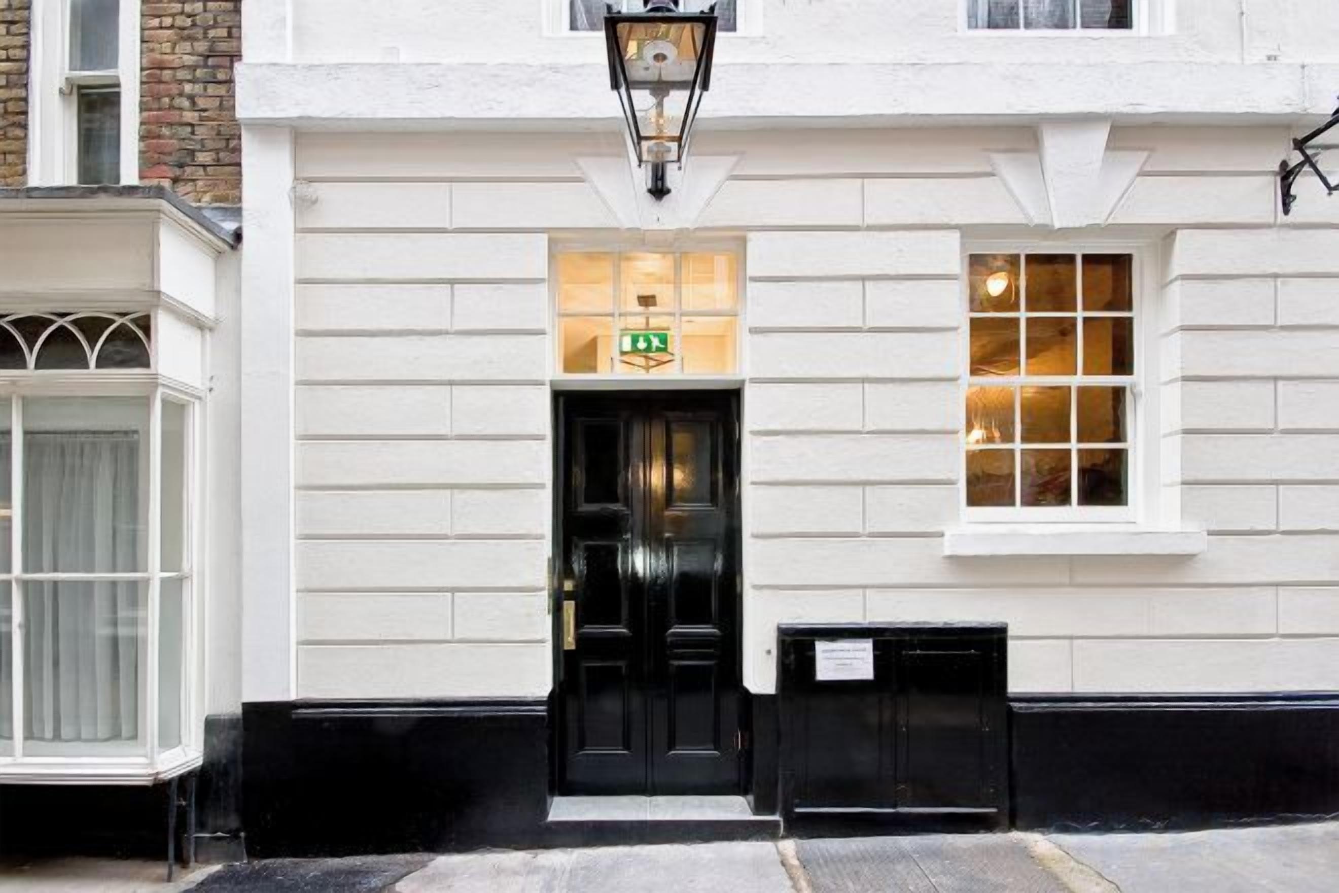 A building with a black door, a sign above the door, and a window to the right.