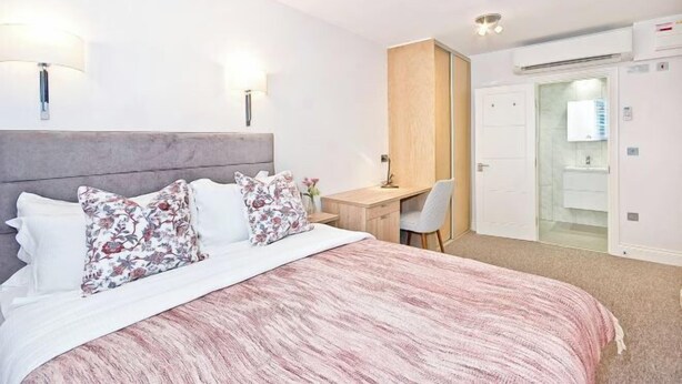 A bedroom with a bed, bedside lamps, a desk, and a wardrobe. - Eldon Chambers Pod 7 by City Living London (London)