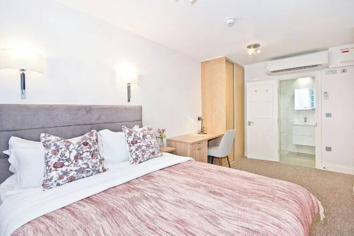Ein Schlafzimmer mit einem Bett, Nachttischlampen, einem Schreibtisch und einem Kleiderschrank.