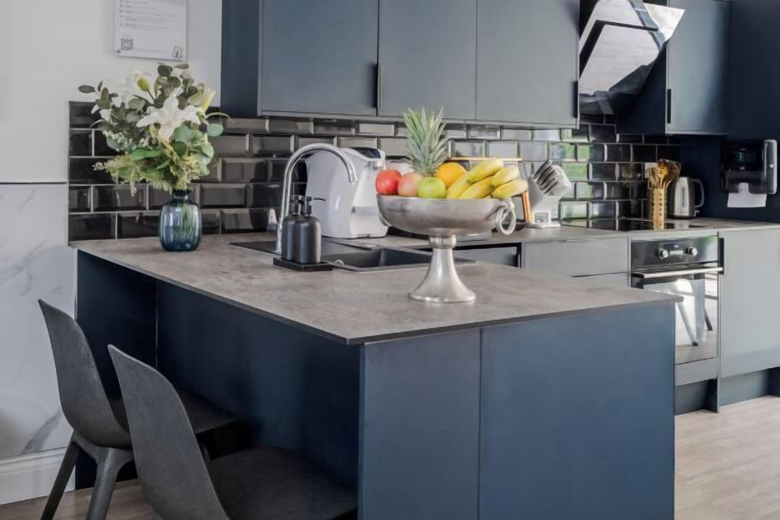 A modern kitchen with a central island, a sink, and a built-in oven.