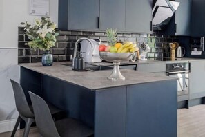 A modern kitchen with a central island, a sink, and a built-in oven. - LONDONERS - Fabulous Four Residence (London)