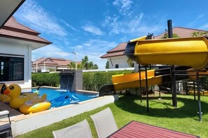 A backyard with a swimming pool, slides, and inflatable toys. - Villa me & you2 (Cha-am)