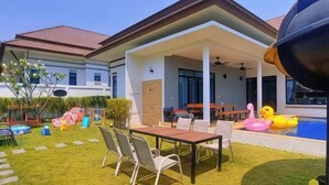 A modern house with a covered patio, a swimming pool, and outdoor furniture. - Villa me & you2 (Cha-am)