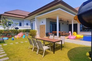 A house with a covered patio, a swimming pool, and outdoor furniture.