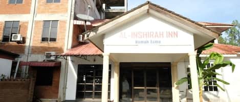 Un edificio con un letrero que dice "AL-INSIRAH INN Rumah Tamul".