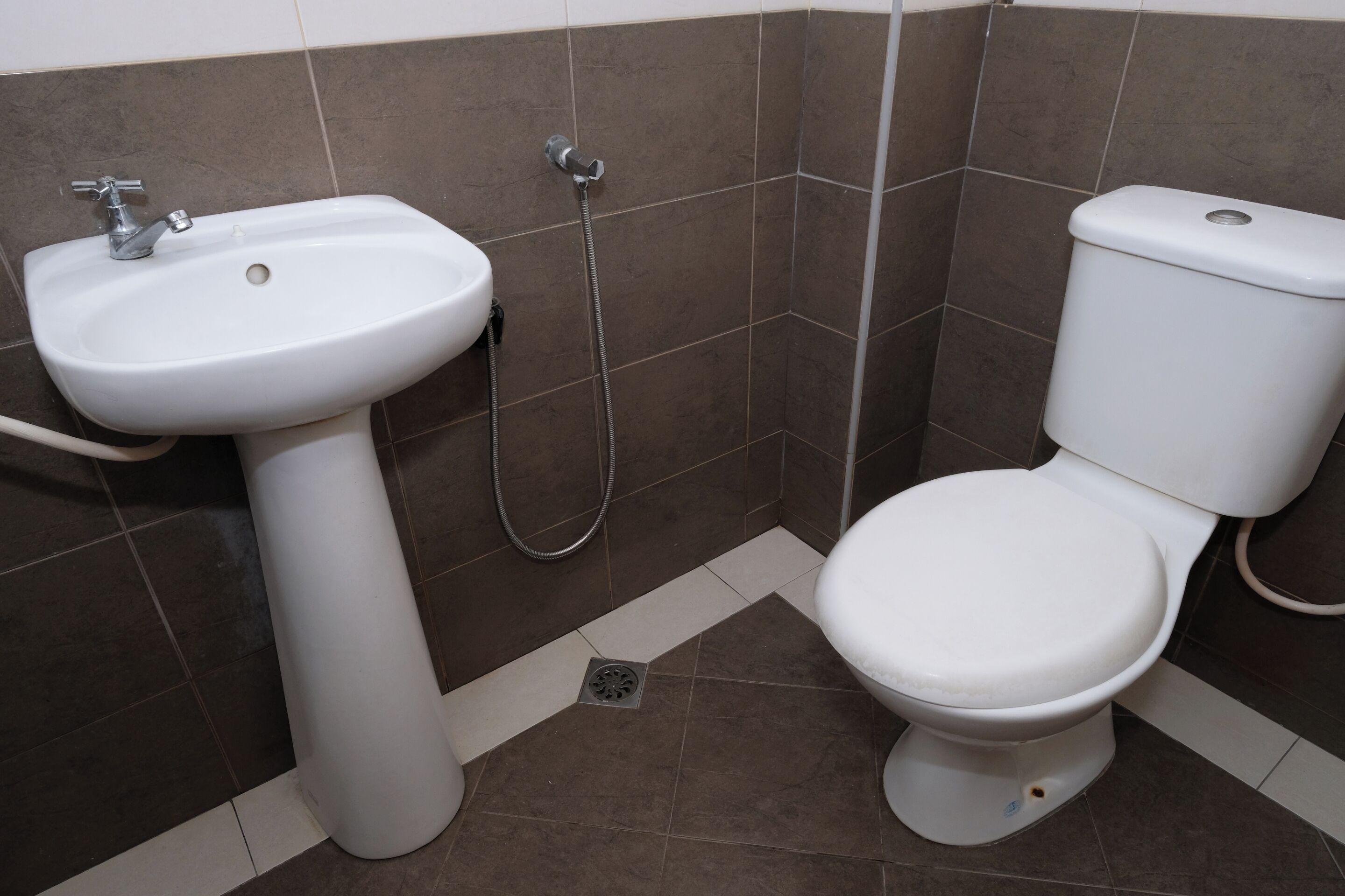 Un baño con lavamanos pedestal blanco, inodoro y ducha.