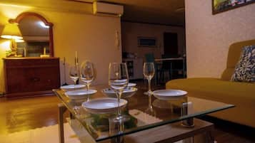 A dining area with a glass table set for four, a sofa, and a lamp.