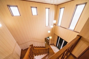 A wooden interior with a staircase, multiple windows, and hanging light fixtures. - wing mihama (Chatan)
