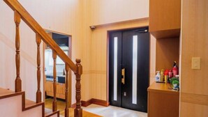 A wooden staircase leading to a room with a black door and a small shelf with cleaning supplies. - wing mihama (Chatan)