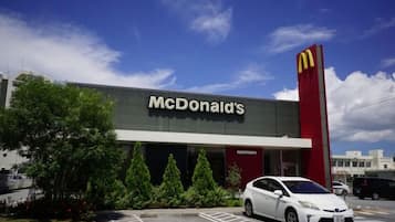 A McDonald's restaurant with a parking lot and a white car parked in front.