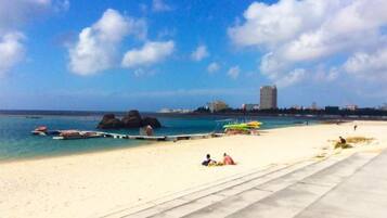 A beach with clear blue water, a pier, and a few people relaxing.