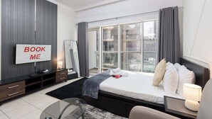 Ein modernes Hotelzimmer mit Bett, Fernseher, Schreibtisch und einem großen Fenster mit Vorhängen.