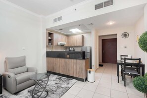 A modern kitchen with wooden cabinets, a black countertop, and a built-in oven. There is a dining area with a table and chairs, and a small potted plant on the wall.
