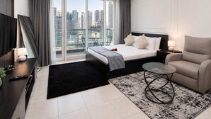 Ein modernes Hotelzimmer mit einem Bett, einer Couch, einem Glastisch und Blick auf die Stadt.