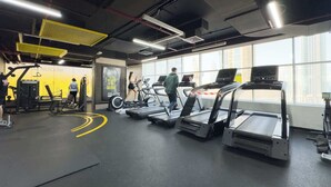 Ein Fitnessstudio mit Laufbändern, Krafttrainingsgeräten und einem großen Fenster.