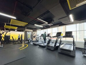 A gym with treadmills, weight machines, and a large window.