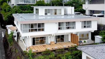 A modern two-story building with a flat roof, large windows, and a wooden deck area.