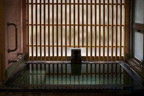 A traditional Japanese onsen with a wooden sliding door and a glass-enclosed hot spring area. - Yu-no-izumi (Ito)