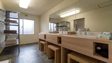 A modern bathroom with a large mirror, dual sinks, and built-in shelves.