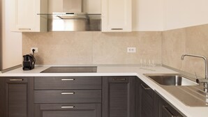 A modern kitchen with dark wood cabinets, a stainless steel sink, and a glass backsplash. - Casa Marina con Patio by Wonderful Italy (Olbia)