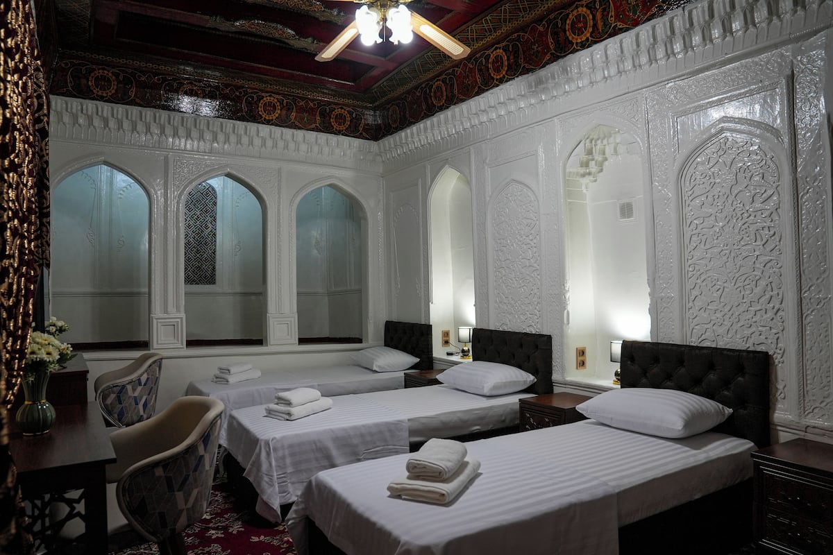 A hotel room with two beds, a desk, and a chair.