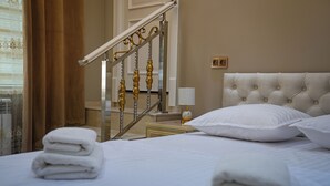 Una habitación de hotel con una cama bien hecha, una lámpara de noche y vistas a la escalera.