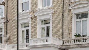 A multi-story building with white-framed windows and a brick facade. - Kensington Standard Room (London)