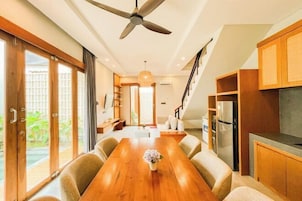 A modern kitchen with wooden cabinets, a built-in oven, and a dining area with a wooden table and chairs.