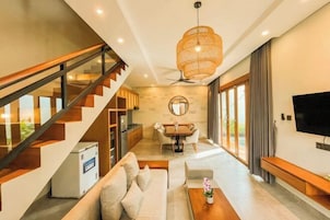 A modern living room with a staircase, a dining area, and a TV.
