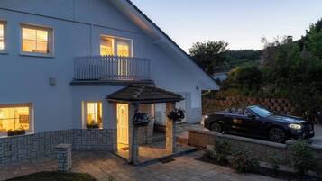 A two-story house with a balcony, a covered patio, and a parked car.